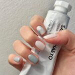 Маникюр на короткие ногти в пастельно-молочной гамме с клетчатым принтом на одном пальце